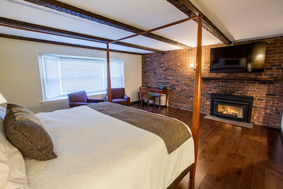 A fireplace king room with a canopy bed and wood flooring