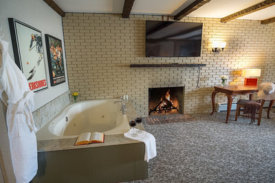 A jacuzzi suite with a jacuzzi tub, fireplace, and a large TV