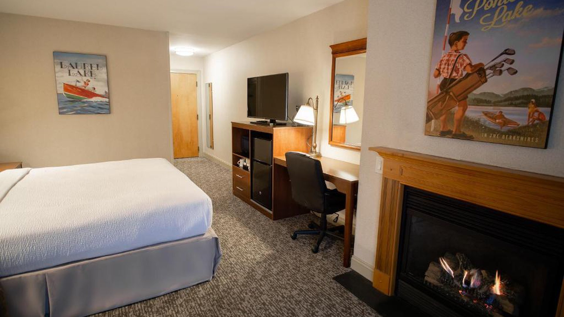 Deluxe King room with gas fireplace, work desk, and Berkshires-themed artwork at The Yankee Inn