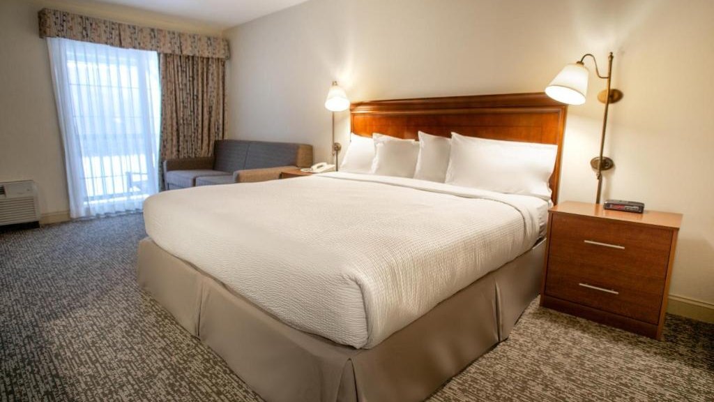 Deluxe King room with upholstered headboard, sitting area, and warm natural lighting at The Yankee Inn