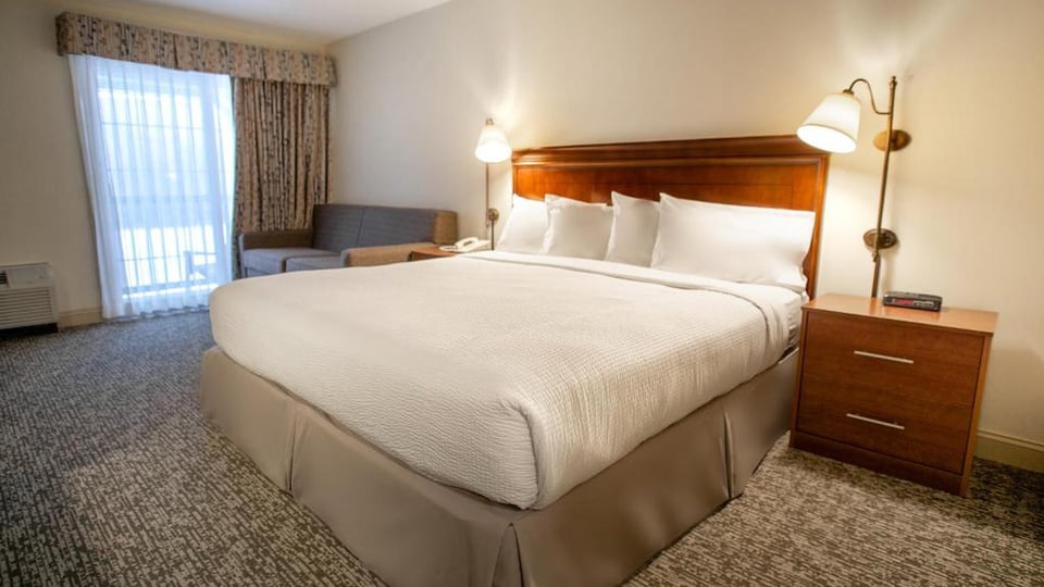 King bed with wooden headboard, plush pillows, and bedside reading lamps in a Deluxe King Mountain View room