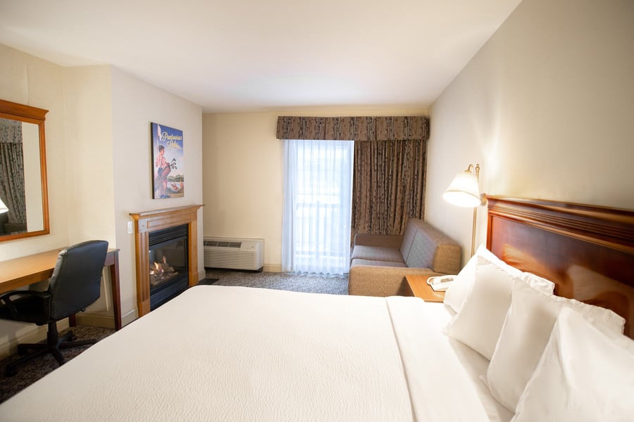 King Deluxe Room with gas fireplace, work desk, pull-out sofa, and king bed with wooden headboard