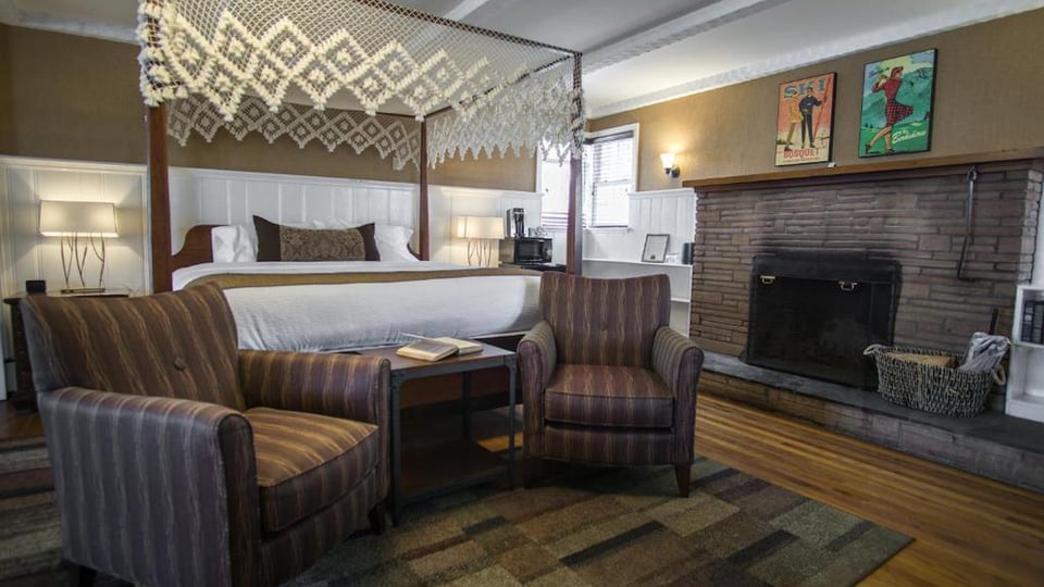 King Superior Room featuring a wood-burning fireplace, vintage Berkshires artwork, and lounge seating at The Yankee Inn in Lenox