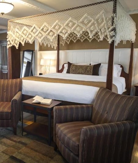 King Superior Room with macramé canopy four-poster bed and upholstered sitting area at The Yankee Inn