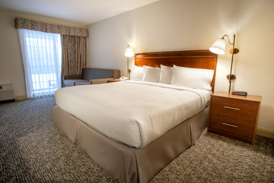 Spacious Deluxe King room with sofa, large window, and bedside reading lamps