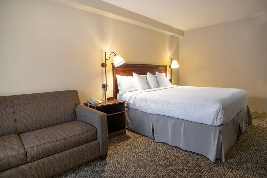 Deluxe King room featuring a king bed, pull-out sofa, and warm ambient lighting in Lenox, MA