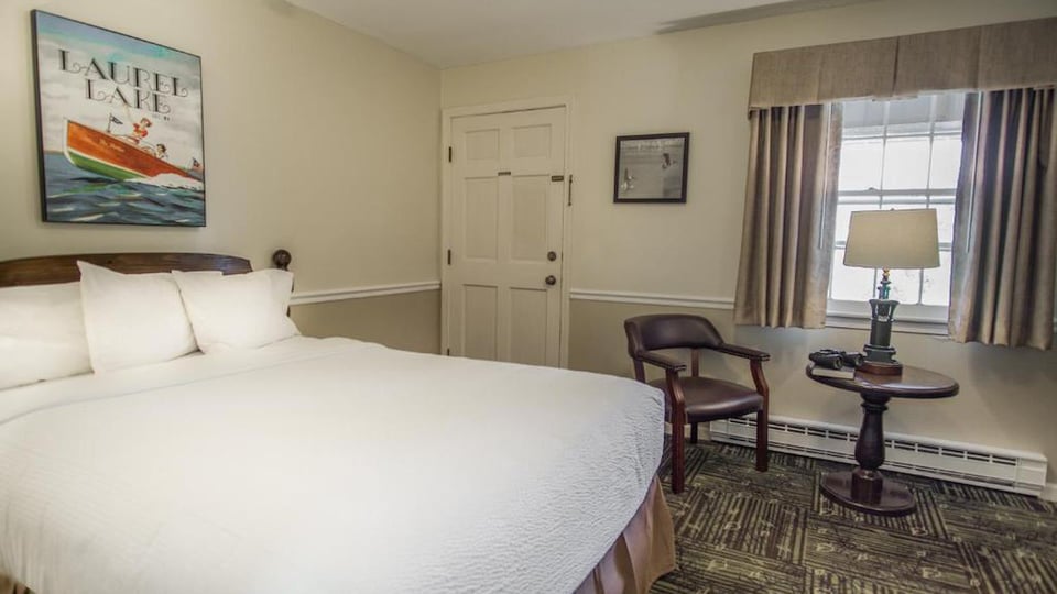 South Lodge Queen room featuring a queen bed, leather sitting chair, and natural light from a curtained window in Lenox, MA
