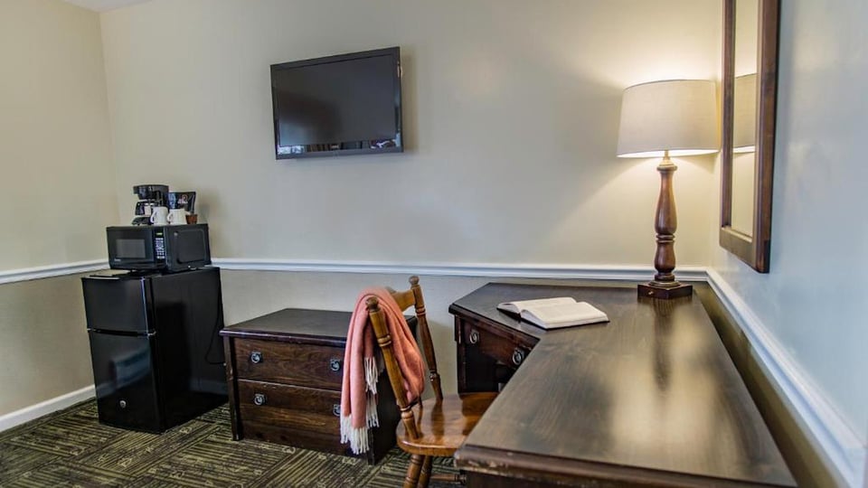 In-room work desk with wall-mounted TV, mini-fridge, microwave, and coffee maker in a South Lodge Queen room