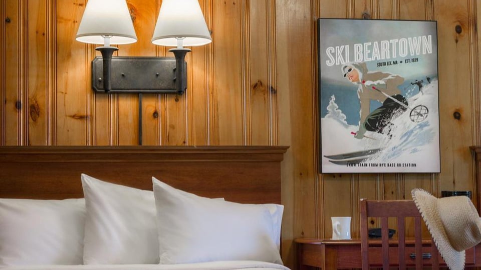 Vintage Ski Beartown South Lee MA poster mounted above the bed beside warm pine wood paneling in a South Lodge guest room