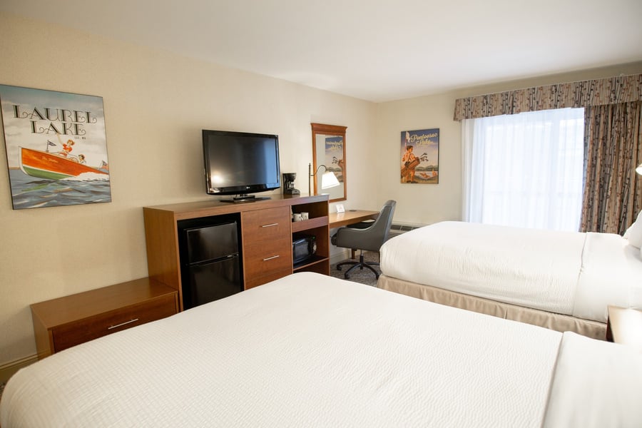 In-room amenity center with flat-screen TV, mini-fridge, coffee maker, and work desk in a Two Queen guest room