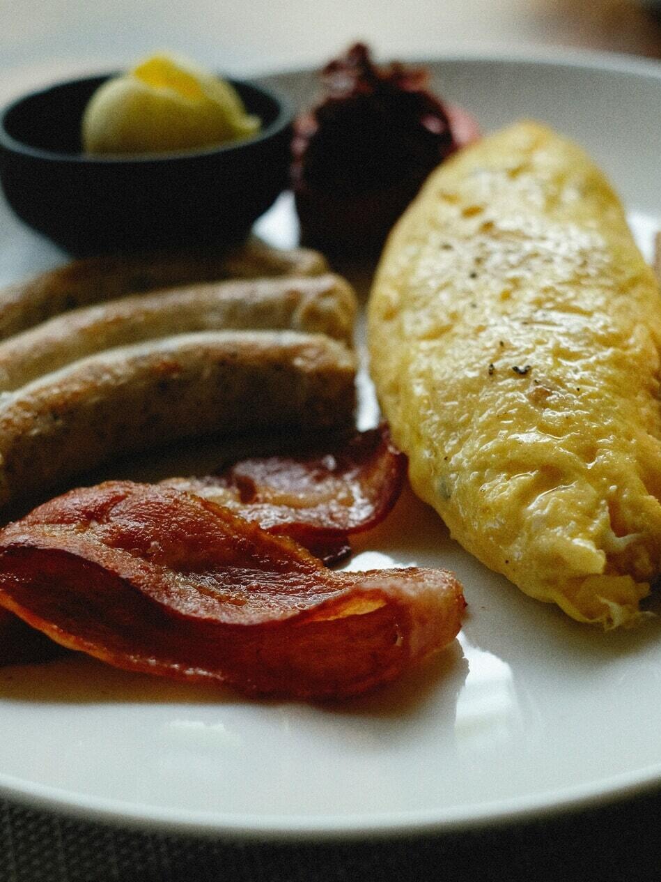 Hot breakfast plate with omelet, breakfast sausages, and crispy bacon served at the complimentary daily breakfast