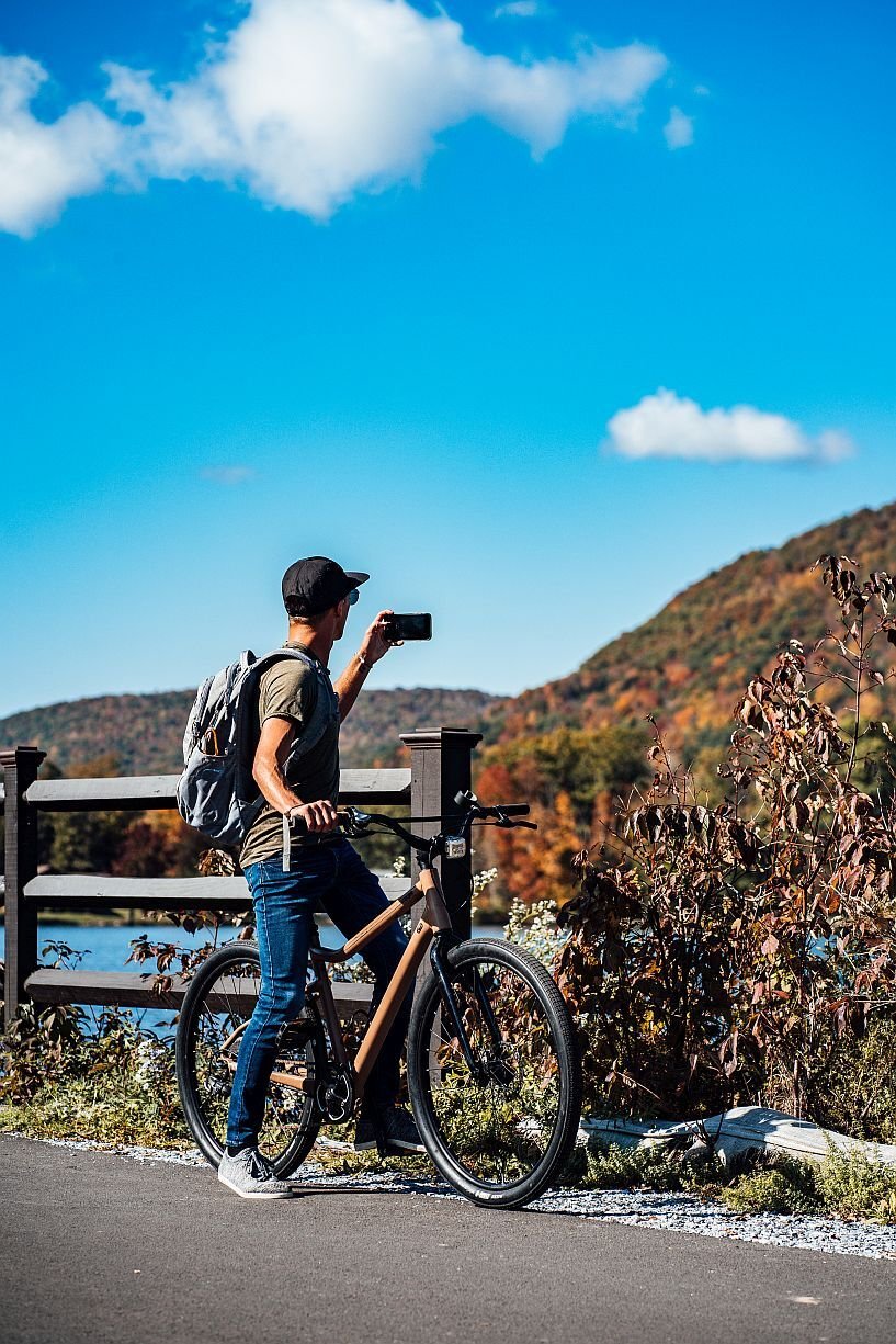 Cyclist on a hilltop overlook photographing autumn foliage across the Berkshire mountains