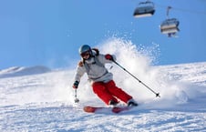 A woman in a red ski suit skiing down a hill