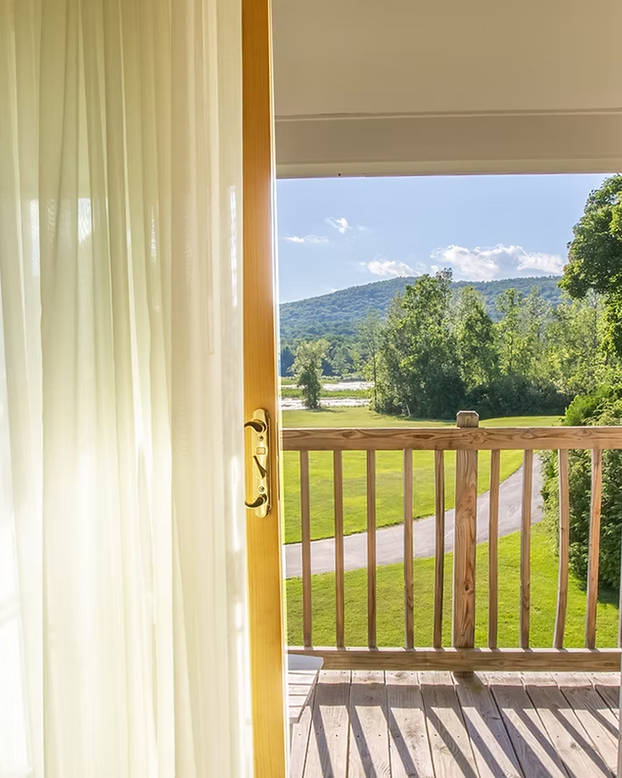 Private guest room balcony with sheer curtains framing rolling Berkshire mountain views