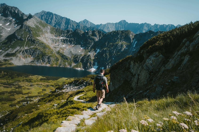 Solo hiker walking a mountain trail with sweeping valley and alpine lake views in the Berkshires