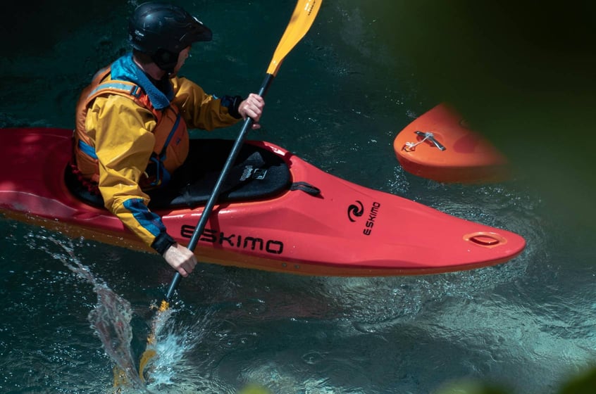 Kayaker in a yellow jacket paddling through rushing water in the Berkshires