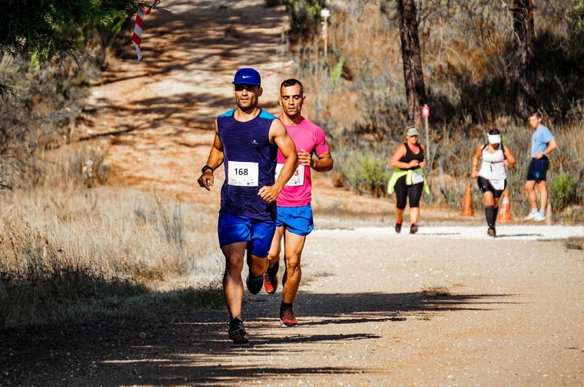 Trail runners racing through a sun-drenched dirt path surrounded by dry brush in the Berkshires