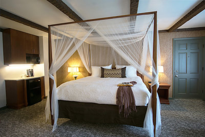 A king canopy bed with sheer linens draped over 